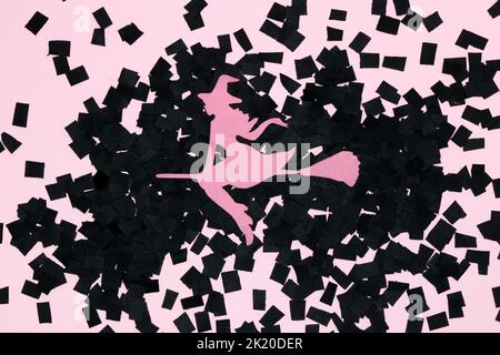 pink paper witch on broom on black part of black and pink background, creative halloween concept, flat lay, paper craft Stock Photo