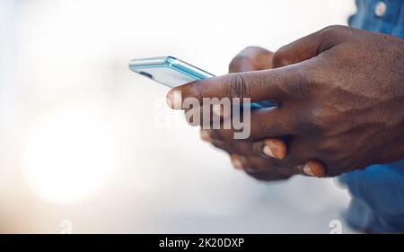 Hands of an african man on a phone networking, doing research on the internet or typing a message. Closeup of a black guy browsing on social media Stock Photo