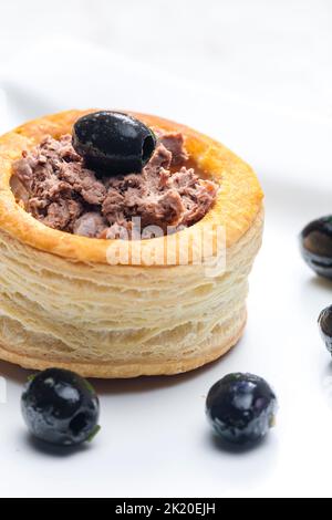 puff pastry filled with terrine served with black olives Stock Photo