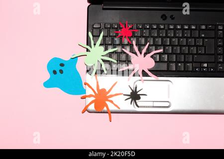 colorful spiders and ghost on laptop keyboard, creative halloween concept, flat lay, paper craft monster Stock Photo