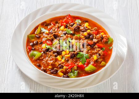 taco soup of ground beef, tomatoes, chopped green chilis, onions, corn, red beans and taco seasoning in white bowl Stock Photo