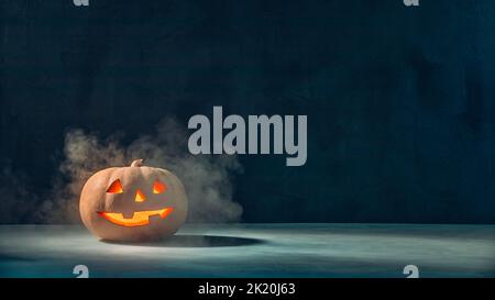 Halloween Jack o'Lantern pumpkin with smoke in the dark Stock Photo