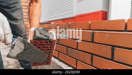 Builder applies cement mortar to red brick close up. Brick building concept. Stock Photo