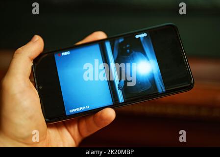 The thief breaks into the house. Security camera on mobile app. Stock Photo
