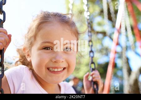 I want to go higher. Portrait of a sweet little girl playing on a swingset. Stock Photo