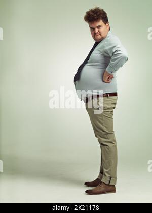 Im awesome. Full length shot of an overweight man viewed from the side. Stock Photo