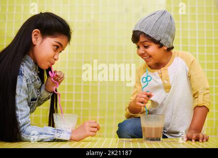 Its all about the slurp. a cute brother and sister drinking milkshakes with straws. Stock Photo