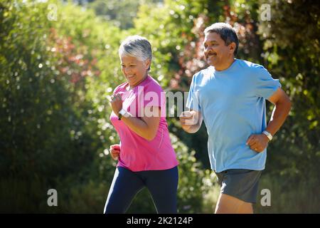 Theyre an active couple. a mature couple jogging together on a sunny day. Stock Photo