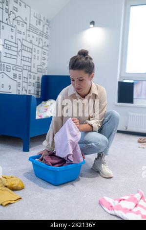 Housewife putting dirty clothes into the wash bowl Stock Photo