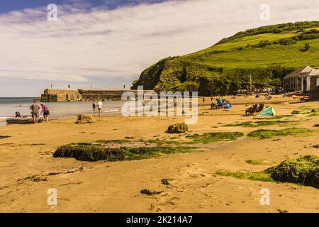 Summers day on the beach at Gorran Haven in Cornwall, people sat on the beach enjoying their holiday. Gorran Haven is a popular holiday village. Stock Photo