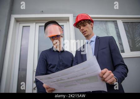 Two engineers at work look at the floor plan to set up the work to be done. Stock Photo