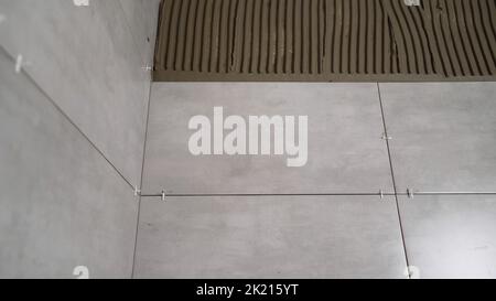 The texture of light gray square glossy ceramic tiles. Grey ceramic tiles on the wall of the house. Gray ceramic tiles in the bathroom. Stock Photo