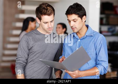 I reckon we could improve the brief. Two friendly colleagues discussing a business portfolio in the office. Stock Photo