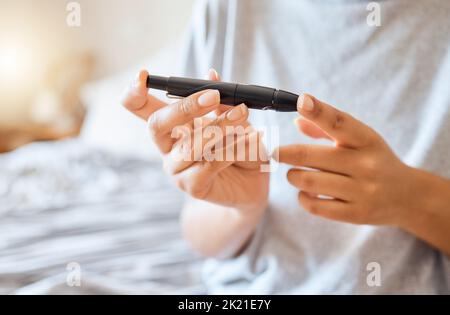 Healthcare, diabetes, and a woman using blood sugar test on finger in bedroom alone. Health, innovation and the daily life of a diabetic lady on bed Stock Photo