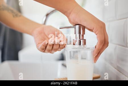Hand washing, hygiene and soap dispenser with woman in bathroom rinsing with water for corona virus, germs or bacteria prevention. Closeup hands for Stock Photo