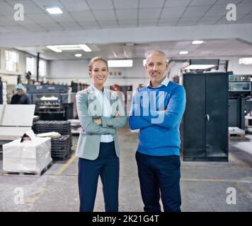 Weve got production sorted. Portrait of two colleagues standing together in a printing factory. Stock Photo