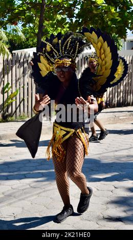 A young Belizean woman having fun and facing the camera in the San Pedro, Belize Carnival 2022. She is dressed in a winged, black and gold costume. Stock Photo