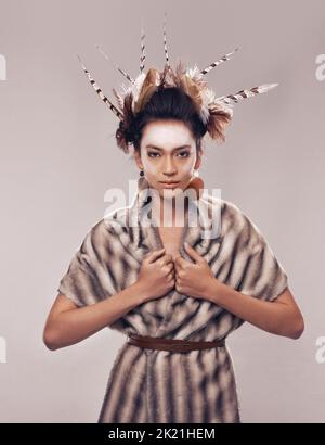 Inspired by her heritage and celebrating her culture. Studio portrait of a young woman in a fur shawl and native american-inspired clothing. Stock Photo