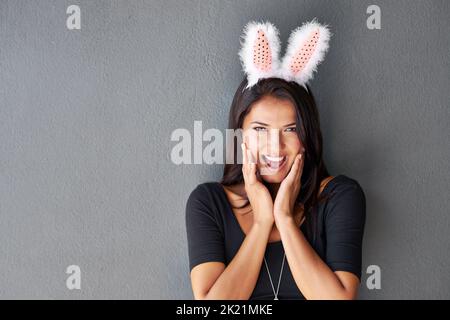 Playing it coy to lure him in. Portrait of a gorgeous brunette wearing bunny ears. Stock Photo