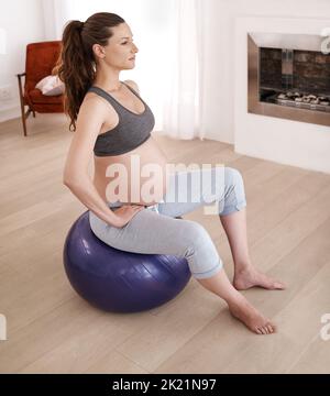 Staying disciplined for her baby. a young pregnant woman exercising at home. Stock Photo