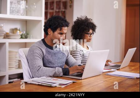 Home admin made easy. a young couple busy on their laptops at home. Stock Photo