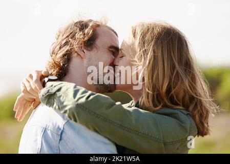 This is happiness...an affectionate young couple sharing a kiss in nature. Stock Photo