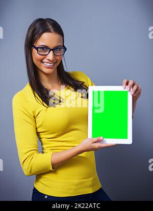 Check out this new website. Studio portrait of an attractive young woman holding a tablet against a blue background. Stock Photo
