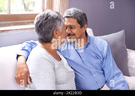 Still showing the same passion. a loving mature couple sitting on their sofa. Stock Photo