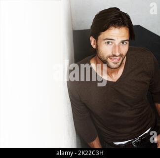 Rustic and rugged. Portrait of a handsome young man leaning against a wall. Stock Photo
