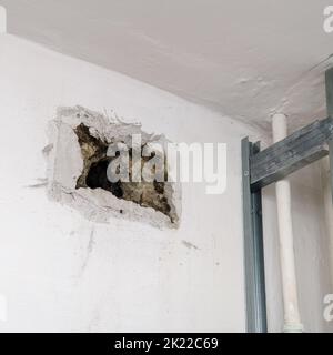 An old dirty uncovered vent in the wall. A hole in the wall uncovered by a grate Stock Photo