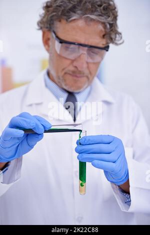 A chemist in action. A cropped shot of a mature scientist conducting an experiment in his lab. Stock Photo