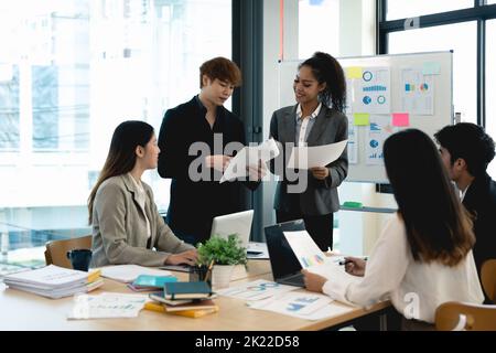 Group of diverse colleagues discussing for financial report with presentation on flipchart during a small conference in the office Stock Photo