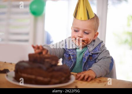 That cake never stood a chance. a young boy eating his birthday cake before the party. Stock Photo