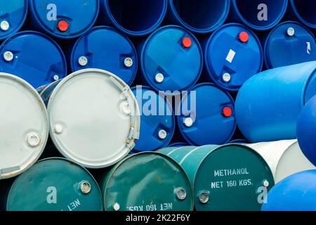 Old chemical barrels. Stack of blue methanol or methyl alcohol drum. Steel chemical tank. Toxic waste. Chemical barrel with toxic warning symbol. Stock Photo