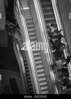 A top view of people on escalator in Genting Highland Theme Park, Malaysia shot in grayscale Stock Photo