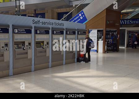 Passengers buying tickets at concourse ticket machines, Waterloo Railway Station, London, UK Stock Photo
