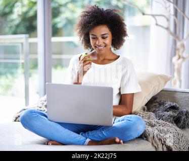 My two favorite apples. a young woman eating an apple while surfing the net. Stock Photo