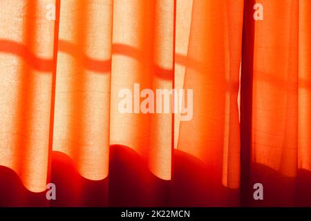 Wavy red tulle curtain in a sunshine. Background photo with selective soft focus Stock Photo
