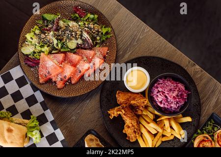 Cafe menu and food assortment. Sashimi fish salad with salmon, vegetables on plate and roast chicken with french fries Stock Photo