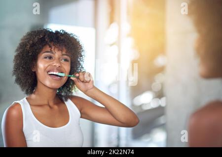 She enjoys keeping her teeth healthy. a young woman brushing her teeth in the bathroom. Stock Photo