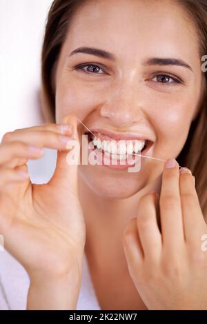 She knows the importance of flossing. Portrait of an attractive young woman holding dental floss and smiling. Stock Photo