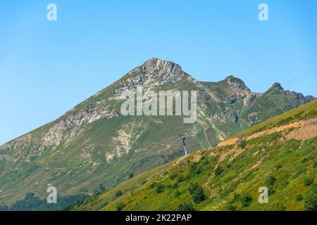 Mountain rock peak and alpine meadows on the southern slope of the ridge Stock Photo