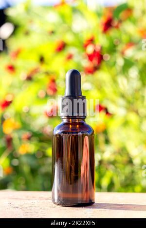 Brown glass dropper bottle with serum, essential oil or other cosmetic product on bright floral background. Natural Organic Spa Cosmetic Beauty Concep Stock Photo