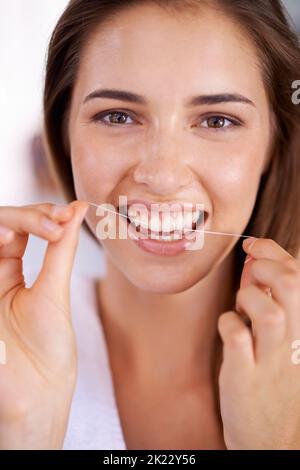 She knows the importance of flossing. Portrait of an attractive young woman holding dental floss and smiling. Stock Photo