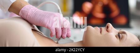 Doctor making ultrasound of thyroid gland to woman patient in clinic Stock Photo