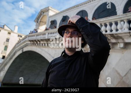 Portrait of a tourist in Venice in front of the Rialto bridge looking to the side, photo with copyspace on the left Stock Photo
