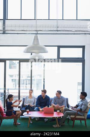 Its all about new strategies. a group of office workers talking together in a meeting room. Stock Photo
