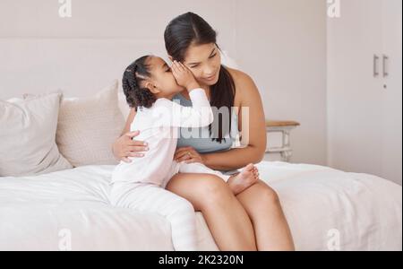 Kids whisper secret in mom ear in home bedroom for trust, love and confidential talk. Care mother listening to young girl child tell privacy story Stock Photo