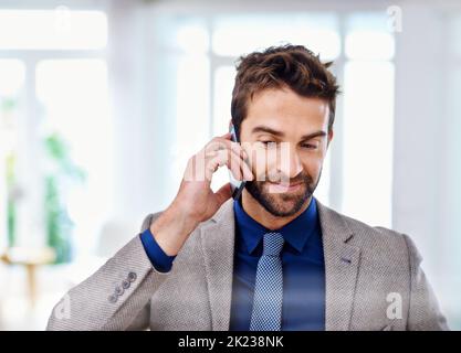 Listening intently. A man in a contemporary suit talking on his cellphone. Stock Photo