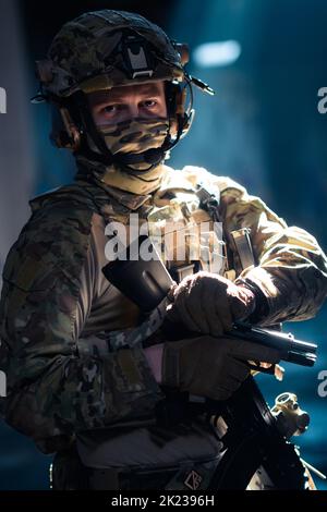 Soldier of army elite forces, special security service fighter with hidden behind mask and glasses face, in helmet and load carriage system, aiming Stock Photo